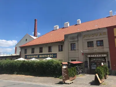 a building with a red roof and a factory at Apartmány Jevany in Jevany