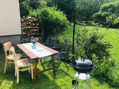 a bbq grill in a backyard with a table and chairs at Apartmán U ŘEKY in Srbsko