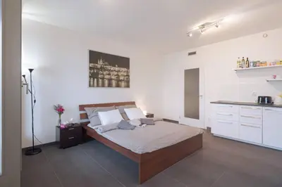 a bedroom with a large bed and a kitchen at Bright studio, 10min to the Centre, free Parking in Prague