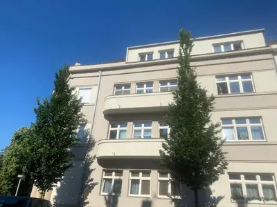 a tall white building with two trees in front of it at Walter&Sons Apartment Centro in Poděbrady