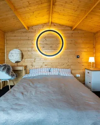 a bedroom with a bed in a wooden wall at Šeberák - ubytování v chatičkách a v luxusních stanech in Prague
