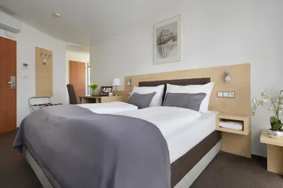 a bedroom with a large white bed and a desk at Prague Season Hotel in Prague