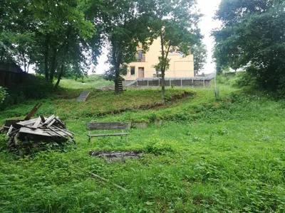 a bench in a field with a house in the background at Slapská přehrada Radíč in Sedlčany
