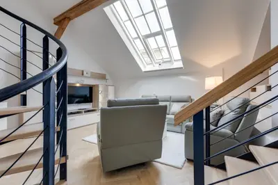 a living room with a staircase with a couch and a television at Wenceslass Square Royal Residence Apartments in Prague