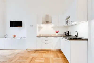 a white kitchen with white cabinets and a wooden floor at Wenceslass Square Royal Residence Apartments in Prague