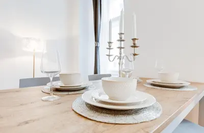 a dining room table with plates and wine glasses at Wenceslass Square Royal Residence Apartments in Prague