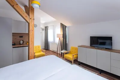 a bedroom with a bed and a tv and yellow chairs at Hotel Restovna in Jíloviště