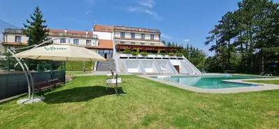 a building with an umbrella next to a swimming pool at Hotel Berounka in Hřebečníky