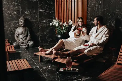 two people sitting on a bench in a room with statues at Hotel Central Park in Poděbrady