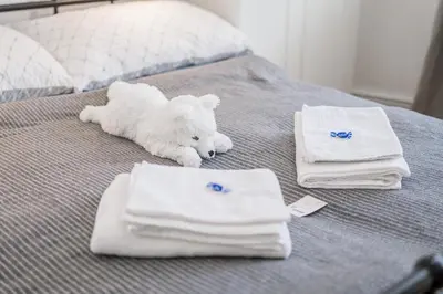 a white teddy bear laying on a bed with towels at Bright downtown studio in Prague