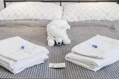a white teddy bear laying on a bed with towels at Bright downtown studio in Prague