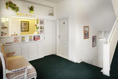 a room with a hallway with green carpet and a chair at Pension Kern in Prague