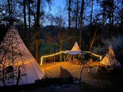 a teepee and a wooden table with a tent at Glamping Nad Meandry in Unhošť