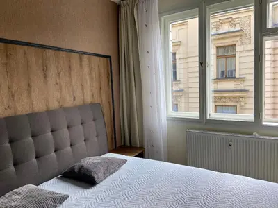 a bedroom with a large bed and two windows at Lokal apartment in Prague