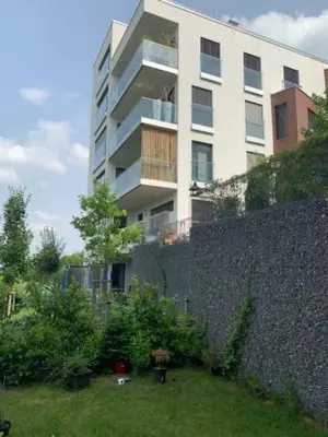 a tall white building with a garden in front of it at byt Panorama Hlubočepy in Prague
