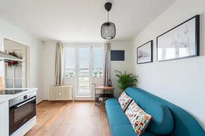a living room with a blue couch and a kitchen at BRIGHT CHARMING Apt with TERRACE, PARKING & AirCo. in Prague