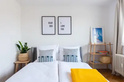 a bedroom with a white bed with three pictures on the wall at BRIGHT CHARMING Apt with TERRACE, PARKING & AirCo. in Prague