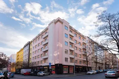 a pink building on a city street with parked cars at BRIGHT CHARMING Apt with TERRACE, PARKING & AirCo. in Prague