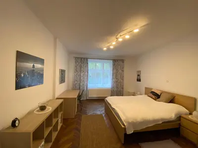 a bedroom with a bed and a desk and a window at Apartman Xaveriova in Prague