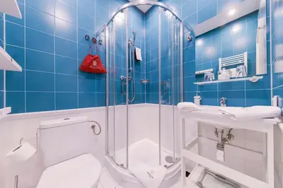 a blue tiled bathroom with a toilet and a shower at Revelton Studios Prague in Prague
