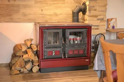 a red stove sitting next to a pile of logs at Útulný domek v zahradě v Unhošti nedaleko letiště in Unhošť