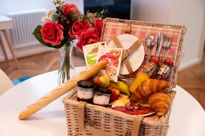 a basket of food on a table with a vase of roses at Pytloun Bristol Residence Prague in Prague