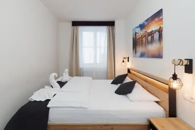 a bedroom with a bed with white sheets and swans on it at Prague Old Town Liliova Garden in Prague