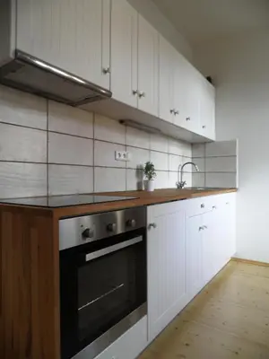 a kitchen with white cabinets and a black oven at Time Cafe & Penzion in Příbram