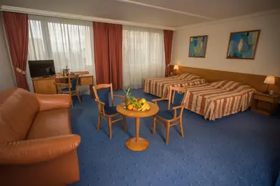 a hotel room with two beds and a table and chairs at TOP HOTEL Praha in Prague