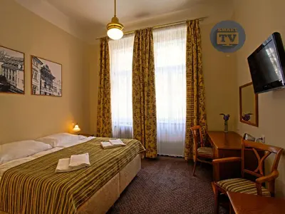a hotel room with a bed and a desk and a television at Anna Hotel in Prague