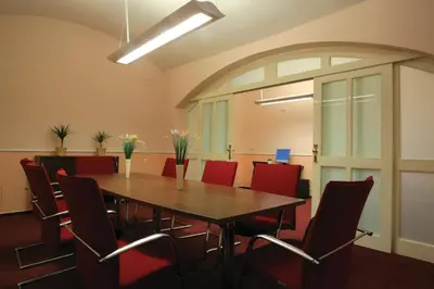 a conference room with a wooden table and red chairs at Anna Hotel in Prague