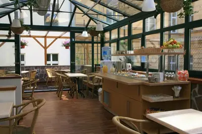 a restaurant with a conservatory with tables and chairs at Anna Hotel in Prague