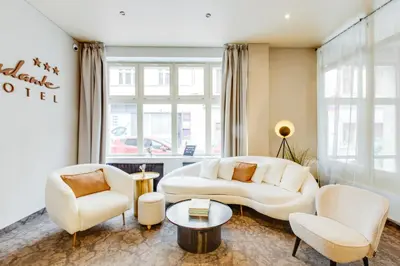a living room with white furniture and a large window at Hotel Andante in Prague