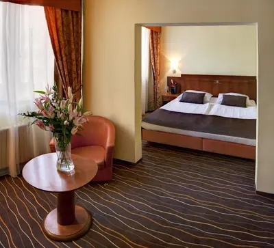 a hotel room with a bed and a vase of flowers at Luxury Family Hotel Bílá Labuť in Prague