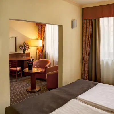 a hotel room with a bed and a table and chairs at Luxury Family Hotel Bílá Labuť in Prague