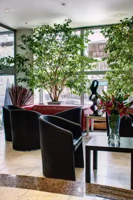a lobby with chairs and a table and trees at Luxury Family Hotel Bílá Labuť in Prague