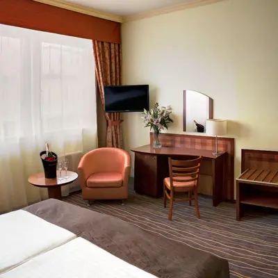 a hotel room with a bed and a desk and chair at Luxury Family Hotel Bílá Labuť in Prague