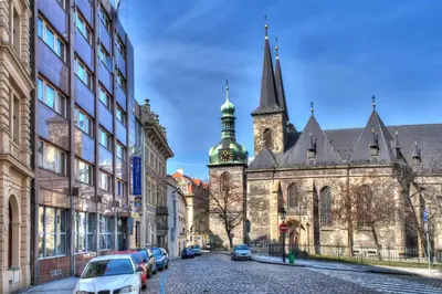an old building with a church and cars parked on a street at Luxury Family Hotel Bílá Labuť in Prague