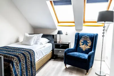 a bedroom with a bed and a blue chair at Hotel Julian in Prague