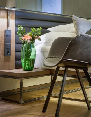 a chair sitting next to a bed with a vase of flowers at Hotel Waldstein in Prague