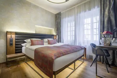 a bedroom with a bed and a desk and window at Hotel Waldstein in Prague
