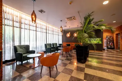 a waiting room with chairs and tables and a plant at Expo Hotel in Prague