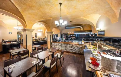 a restaurant with wooden tables and chairs and a cafeteria at Hotel Elite Prague in Prague