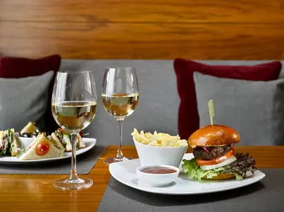 a table with two glasses of wine and a sandwich and fries at K+K Hotel Fenix in Prague