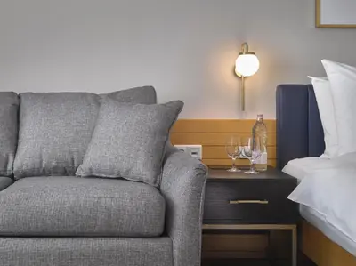 a gray couch sitting next to a bed with wine glasses at K+K Hotel Fenix in Prague