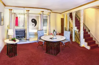 a large bathroom with a tub and a table and chairs at Hotel Hoffmeister in Prague