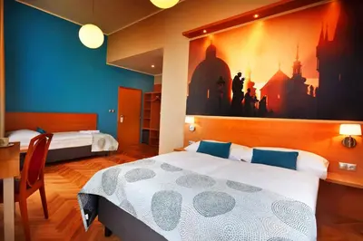 a bedroom with two beds and a desk and a painting on the wall at Hotel Adler - Czech Leading Hotels in Prague