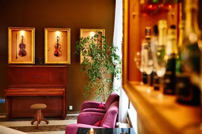 a living room with two purple couches and a piano at Hotel Adler - Czech Leading Hotels in Prague