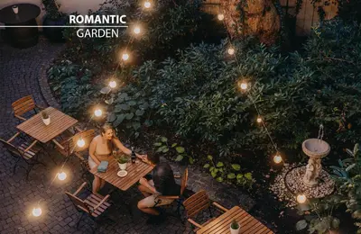 people sitting at a table in a garden at night at Hotel Adler - Czech Leading Hotels in Prague