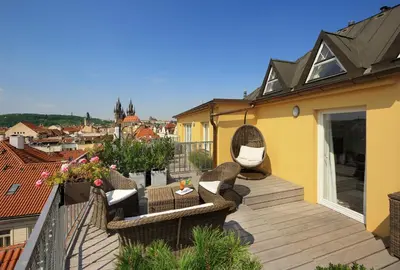 a balcony with wicker chairs and tables on a building at Grand Hotel Bohemia in Prague